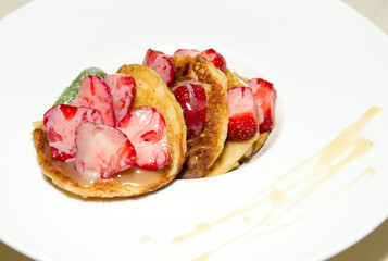 Fresh strawberries with baked pancakes and mint leaf in sugar sauce. Selective focus.