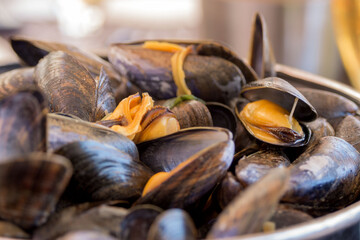 Cooked mussels in garlic sauce in a black saucepan on a table in a fish restaurant. Delicious lunch with seafood and beer. Gastronomic travel. Close-up