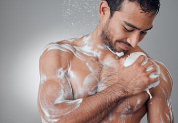 Lather it up. Shot of a young man taking a shower against a grey background.