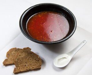 Red borsch in a dark plate and two slices of bread. Beetroot soup.
