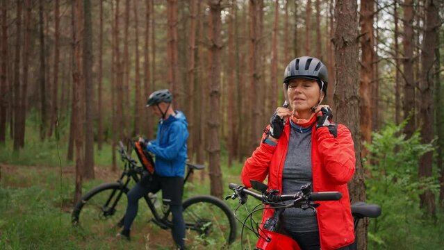 Senior couple bikers outdoors in forest in autumn day.