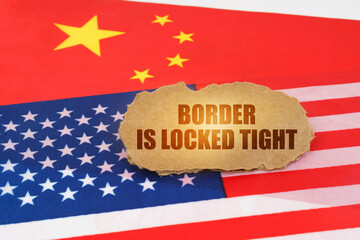 On the flags of the USA and China lies a cardboard sign with the inscription - Border is locked tight