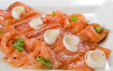 Slices of red fish fillet on a white plate with eggs and herbs.