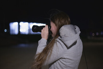 professional photographer or amateur using dslr camera to take pictures at night in the city with...