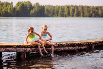 children sit on the bridge by the water, splashes, summer, happiness