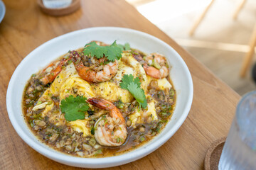Creamy omelette with shrimps and garlic on rice in wood table. Delicious and easy menu.