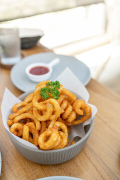 Golden Spicy Seasoned Curly Fries on rustic plate. fast food snack with ketchup on restaurant background. Unhealthy junk food. ready to eat