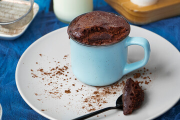 mugcake is microwaved. Homemade cupcake in a mug is on a plate. Chocolate brownie mug cake. Easy cooking concept, microwave baking. muffin chocolate. ingredients, eggs, milk, cocoa.