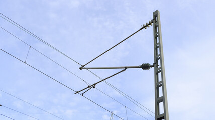 Fototapeta premium Ein Strommast mit Oberleitungen für den Zugbetrieb.