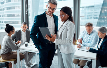 Be smart about your business processes. Shot of two businesspeople using a digital tablet in an...
