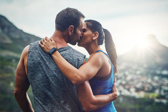 Unexpected kisses are the best. Shot of a young attractive couple training for a marathon outdoors.
