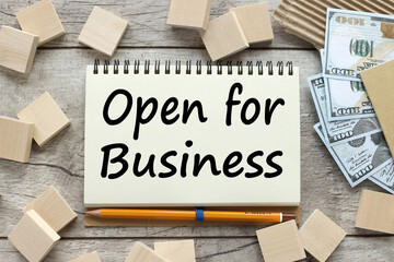 open for business text on open notebook near wooden cubes