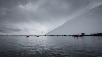 Abenteurer fahren per Kajak entlang von schneebedeckten Eisbergen durch die Antartkis