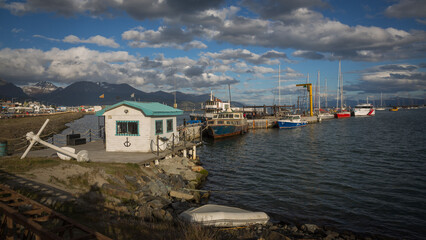 Ein Hafenhäusschen im Hafen von Ushuaia mit kleineren Schiffen und Booten an der Kaimauer