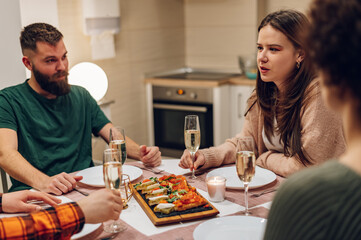 Group of friends enjoying dinner while sitting at the kitchen table together