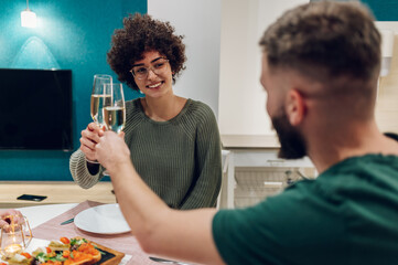 Friends sitting at a kitchen table and toasting during a dinner part