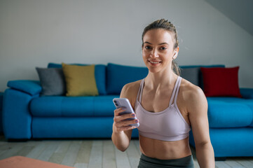 Obraz na płótnie Canvas Woman using airpods and a smartphone while training at home