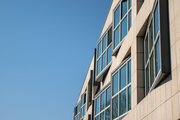 building, modern windows: on an eclectic facade of a small portion of an anonymous building, reflecting the blue sky.