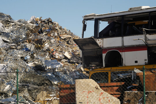 Old broken bus with metal trash mountain background, clear sky