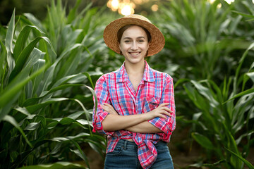 Portrait of young woman farmer inspecting corn field in summer sunny day