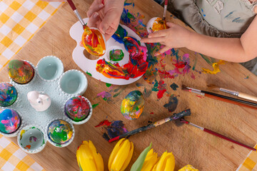 Child painting easter eggs . Decoration egg for seasonal holiday. Handmade craft, fun and artwork together. Colorful childhood with paints. Hands of mum and daughter. Close up.