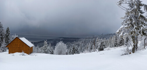 Panorama of winter calm mountain landscape with red shed or barn and mount ridge behind polish mountain named turbacz in Poland