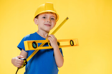 The preschooler holds a construction level in his hands, dreams of becoming a builder