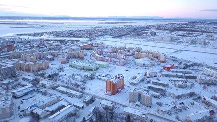 Classic homes under deep, fresh snow, early morning in Winter. Clip. Arial view of a small frozen town located by the river.