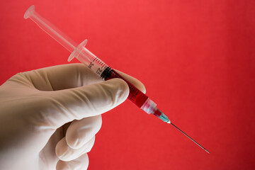 Blood donation topic, doctor hand holding a syringe with blood