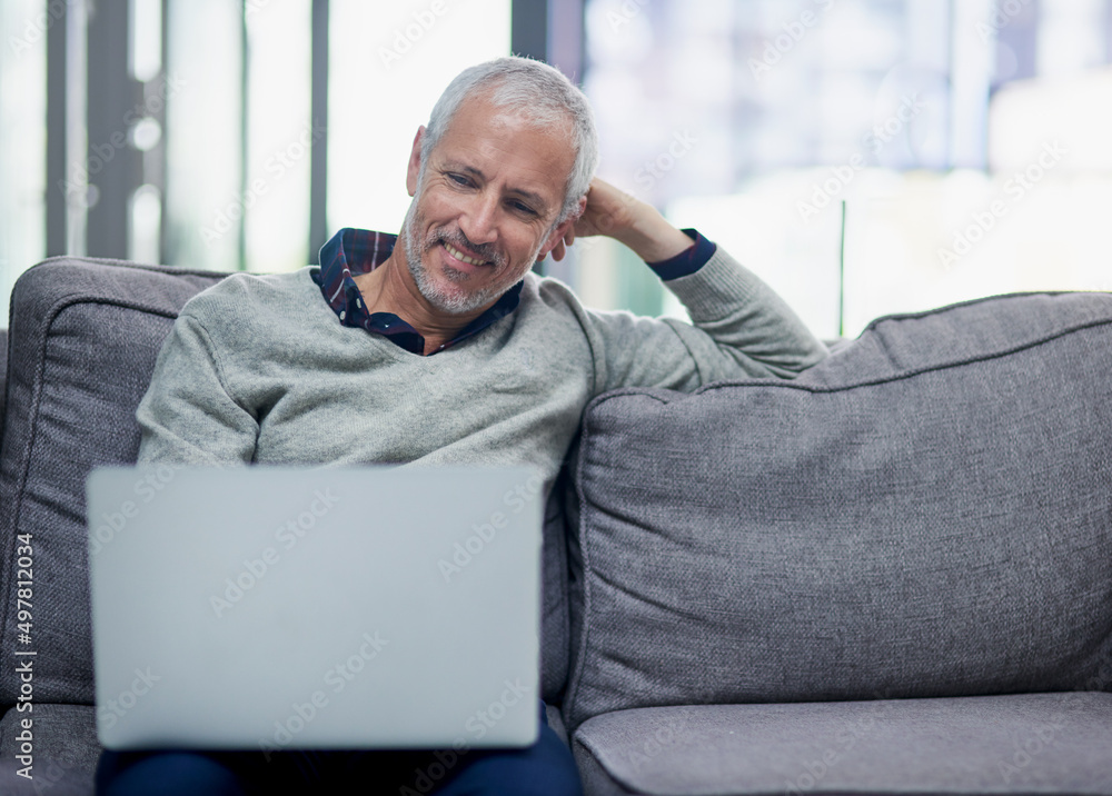 Poster enjoying a relaxed moment in the office. shot of a mature businessman using a laptop while sitting o