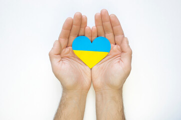 The concept of ending the war in Ukraine. Heart in the colors of the flag of Ukraine in men's hands