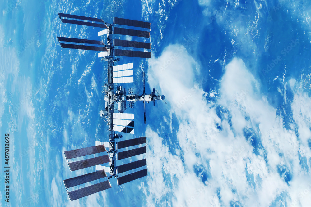 Wall mural iss over the planet, against the background of clouds. elements of this image furnished by nasa