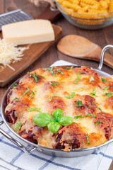 Mac and cheese with meatballs, mozzarella, tomato sauce and basil, in metal backing dish, vertical
