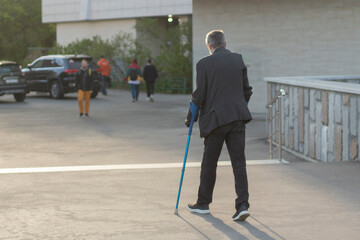 Fototapeta na wymiar A man with crutches in the city. The guy broke his leg.