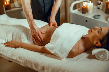 Obraz na płótnie Canvas Relaxed female client getting stomach massage in spa salon. Therapy, alternative medicine
