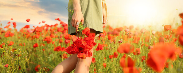 Beautiful young woman with bouquet of poppy flowers in field