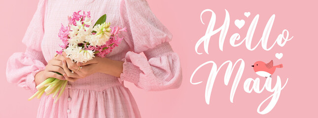 Beautiful young woman with bouquet of flowers and text HELLO, MAY on pink background