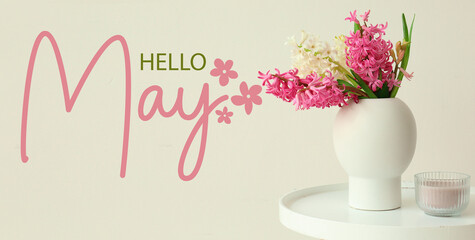 Vase with hyacinth flowers, candle and text HELLO, MAY on light background