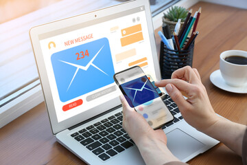 Woman with laptop and smartphone checking her e-mail at table, closeup