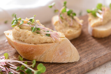 Board with piece of bread and tasty hummus, closeup