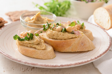 Plate with pieces of bread and tasty hummus on table, closeup