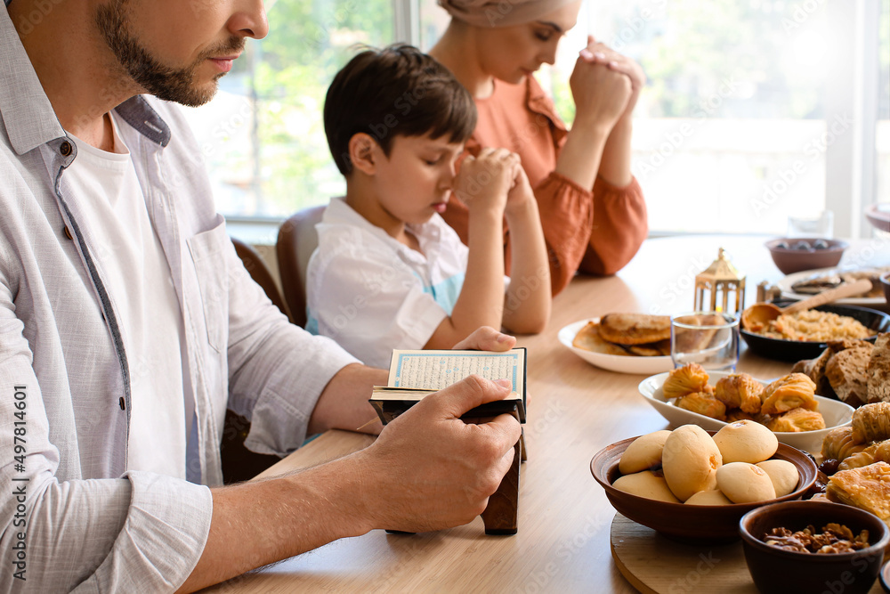 Wall mural Muslim family praying together before breakfast. Celebration of Eid al-Fitr