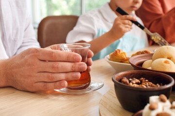 Man with cup of hot Turkish tea at table during breakfast. Celebration of Eid al-Fitr