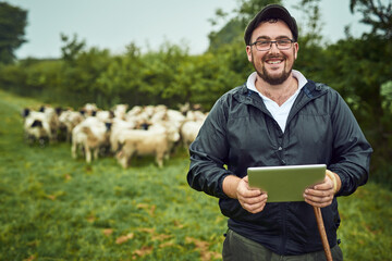 Sometimes I need to check the tablet. Portrait of a cheerful young farmer standing with a digital...