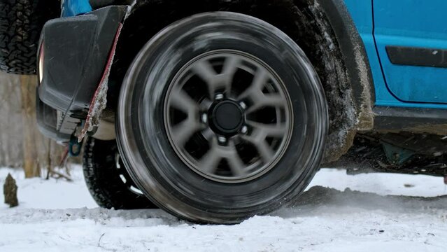 close up view of offroad wheel, car is stuck in snow and can not go further. off-road tire of SUV scrolls in place and car cannot drive out. concept of summer tires on snowy road.