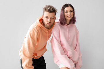 Cool young couple in hoodies on light background