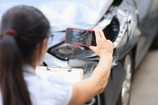Agent takes smartphone photo of damage to car after accident