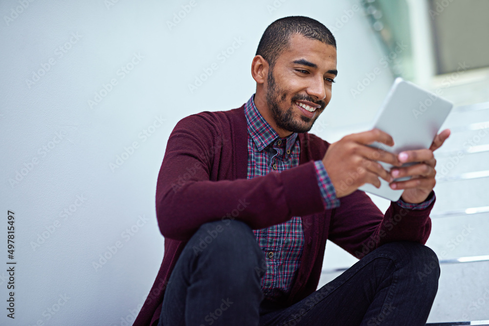 Poster Technology is always at his side. Cropped shot of a young businessman using a digital tablet on the stairs in a modern office.