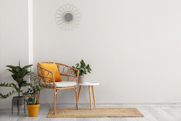 Comfortable armchair, houseplants and table near white wall