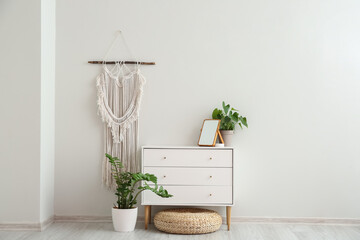 Modern chest of drawers and houseplants near white wall